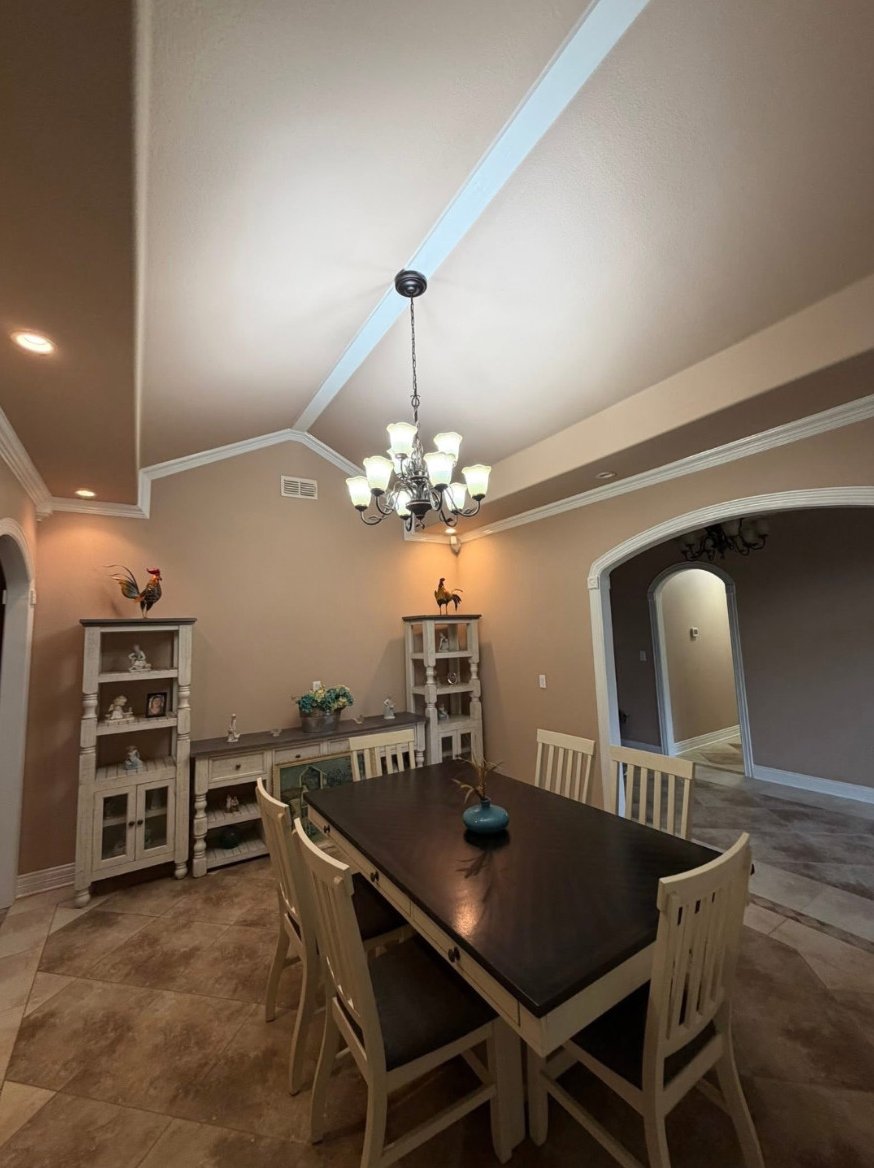 Dining room with a vaulted ceiling, white crown molding and an arched opening.