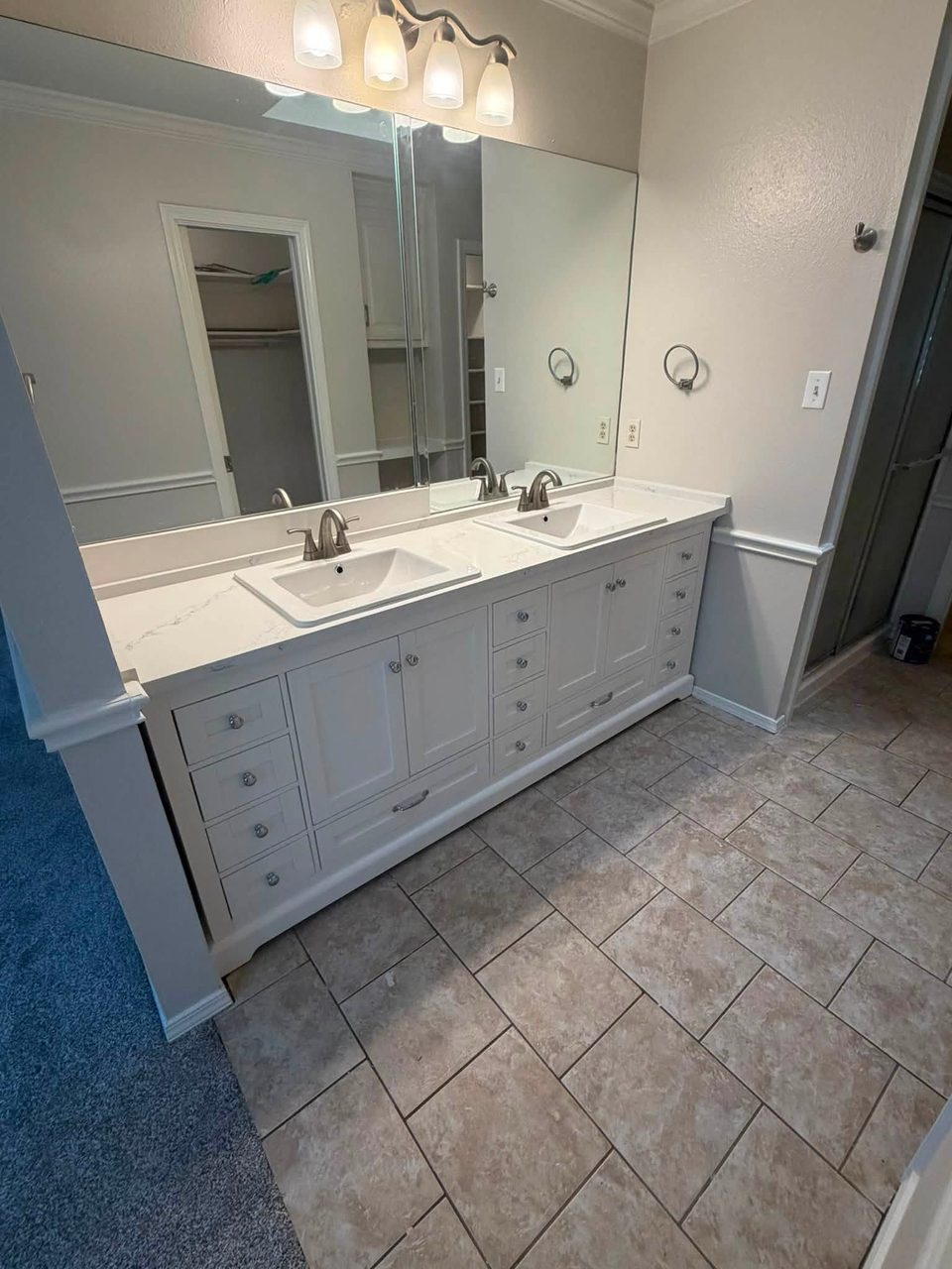 Double-sink bathroom vanity with white cabinets and tiled floor.