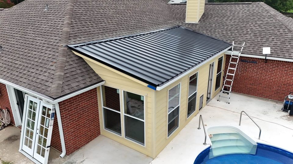 Rear house enclosure with metal roof beside a swimming pool.