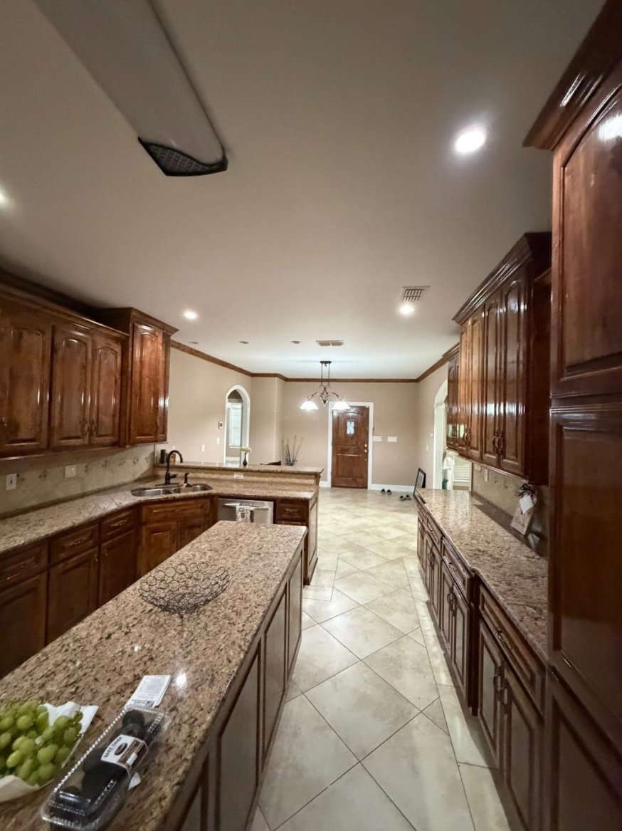 Kitchen with wood cabinets, an island, patterned countertops and diagonal floor tiles.