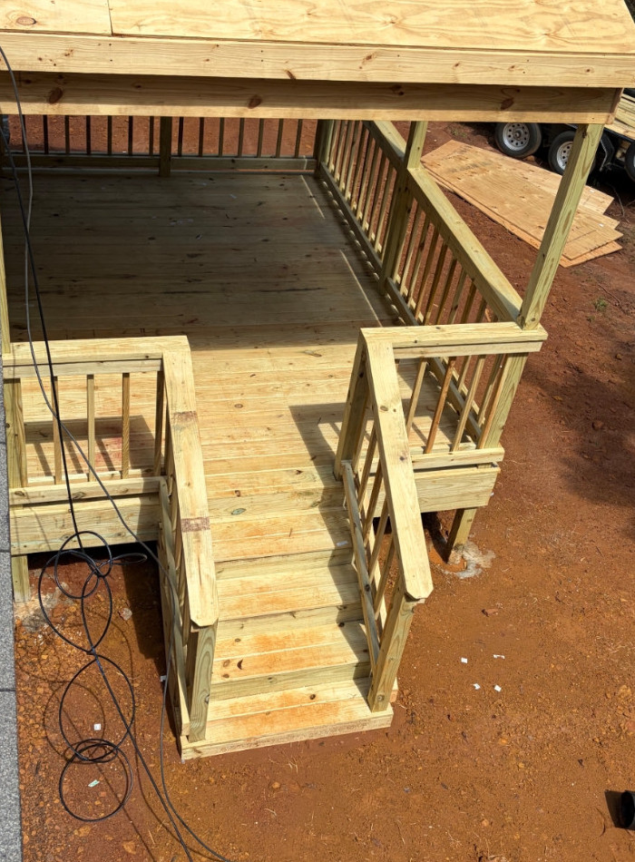 Raised wood deck with stairs, railings and exposed wood framing, viewed from above.